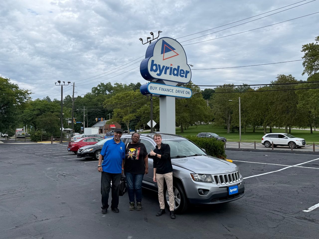 Byrider Euclid customers and salesperson beside their used Jeep Compass at the Euclid, Ohio dealership