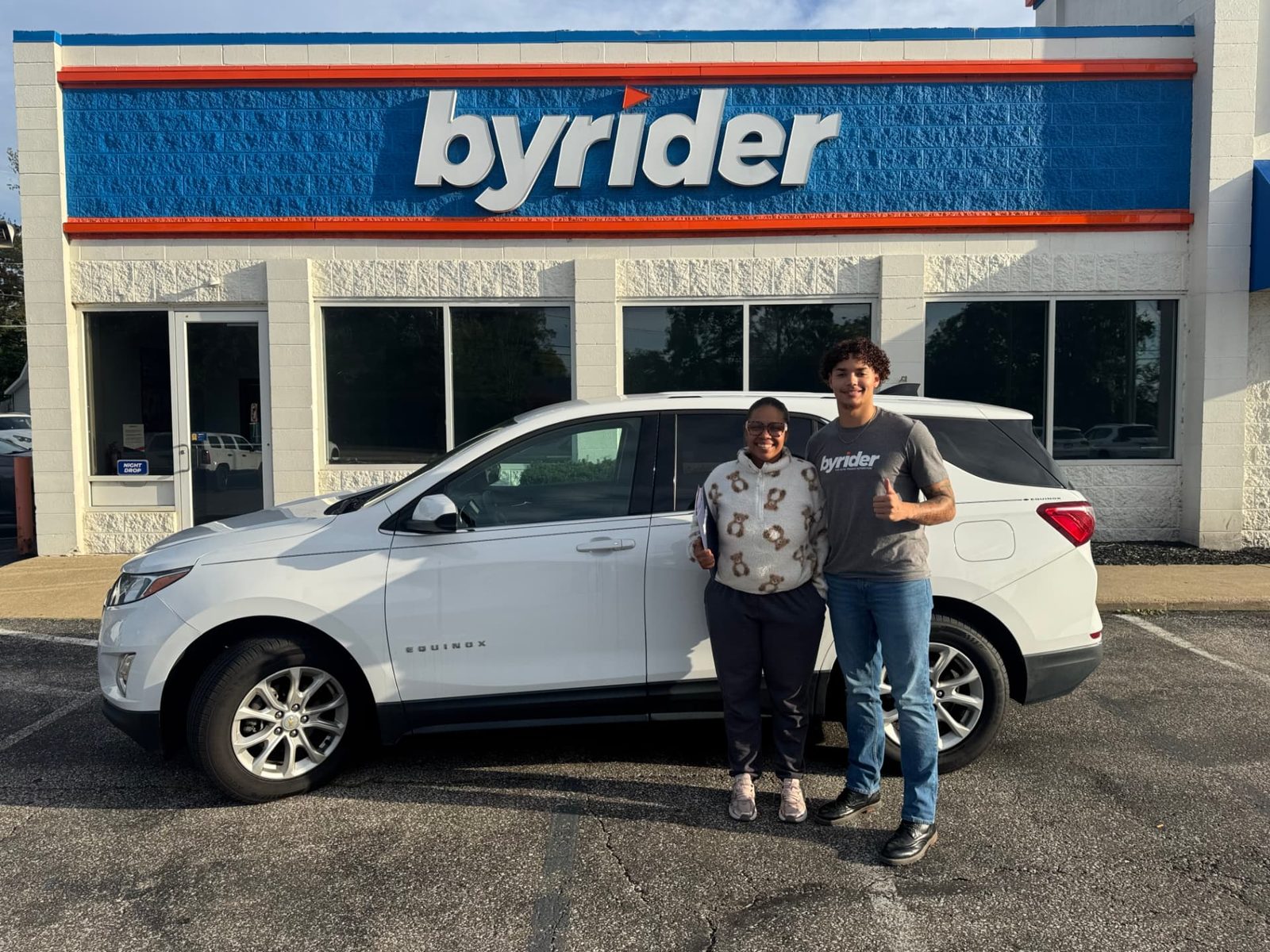 Byrider Ashtabula customer and salesperson beside their used Chevrolet Equinox at the Ashtabula, Ohio dealership