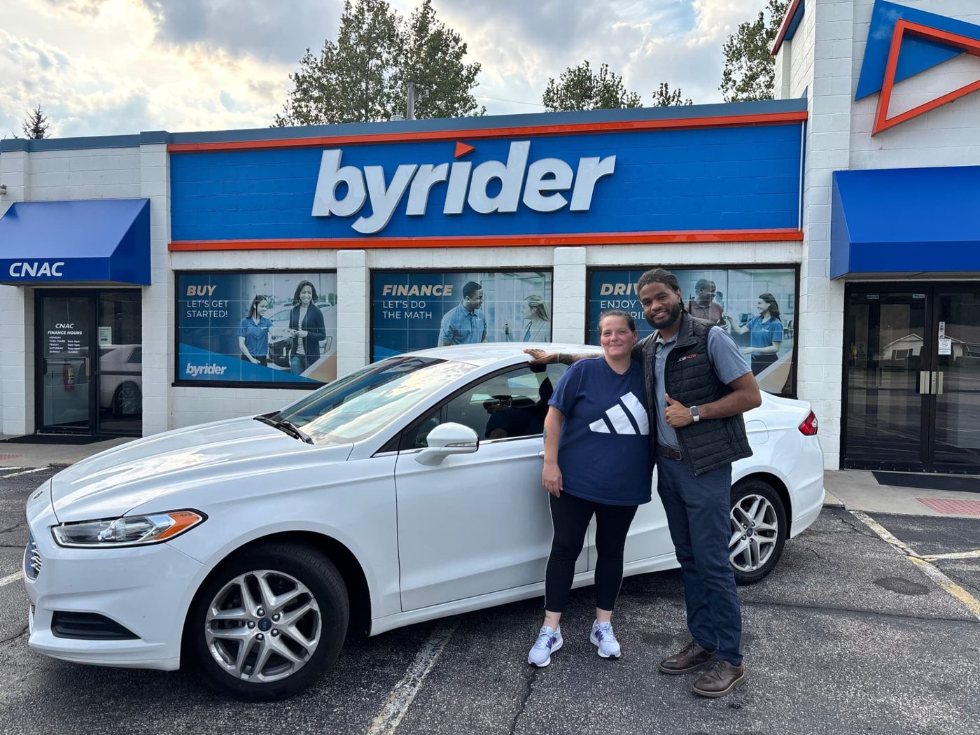 Byrider Amherst customer and salesperson beside their used Ford sedan at the Amherst, Ohio dealership