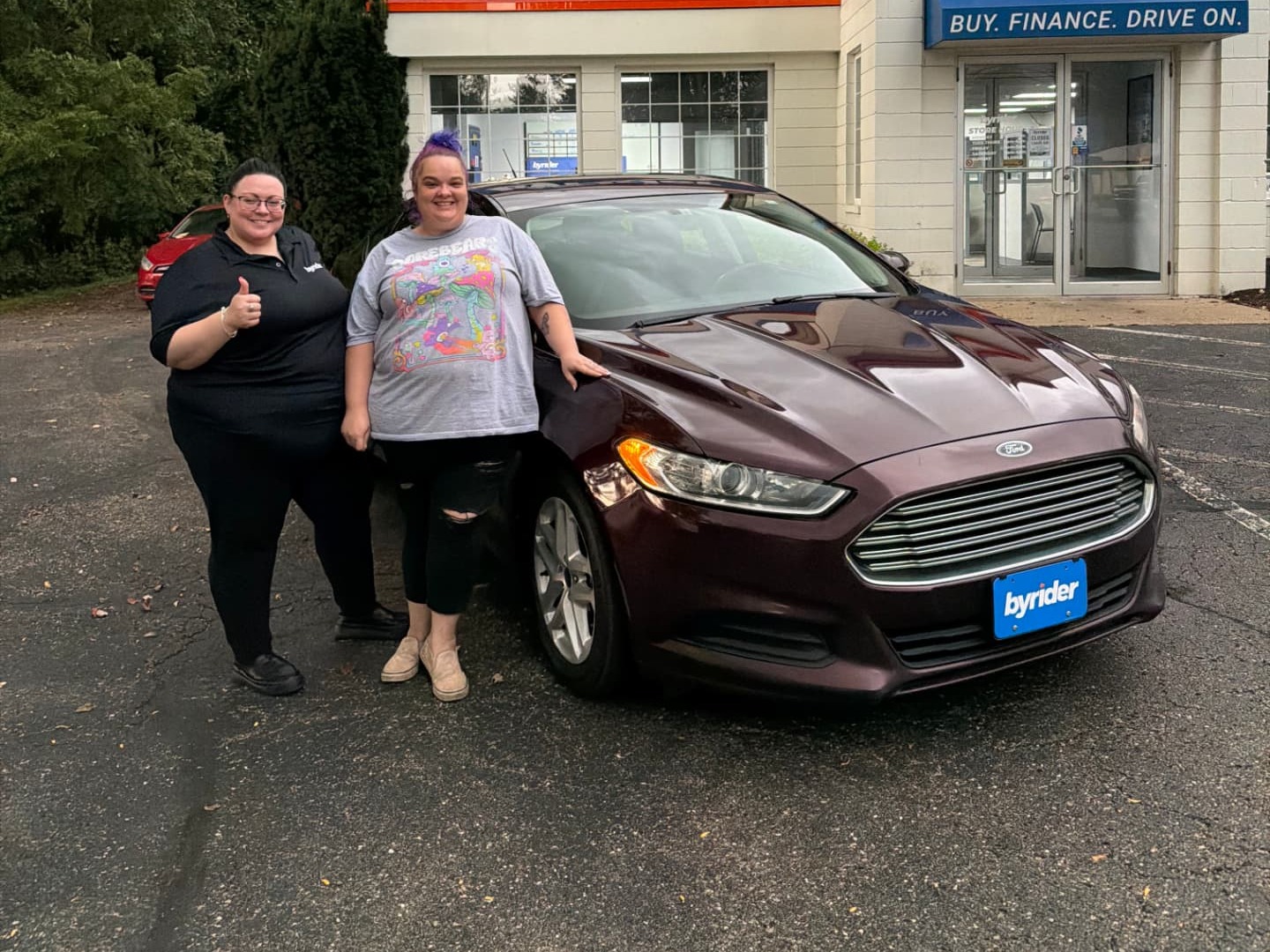 Byrider Wooster customer and salesperson beside their used Ford Fusion at the Wooster, Ohio dealership