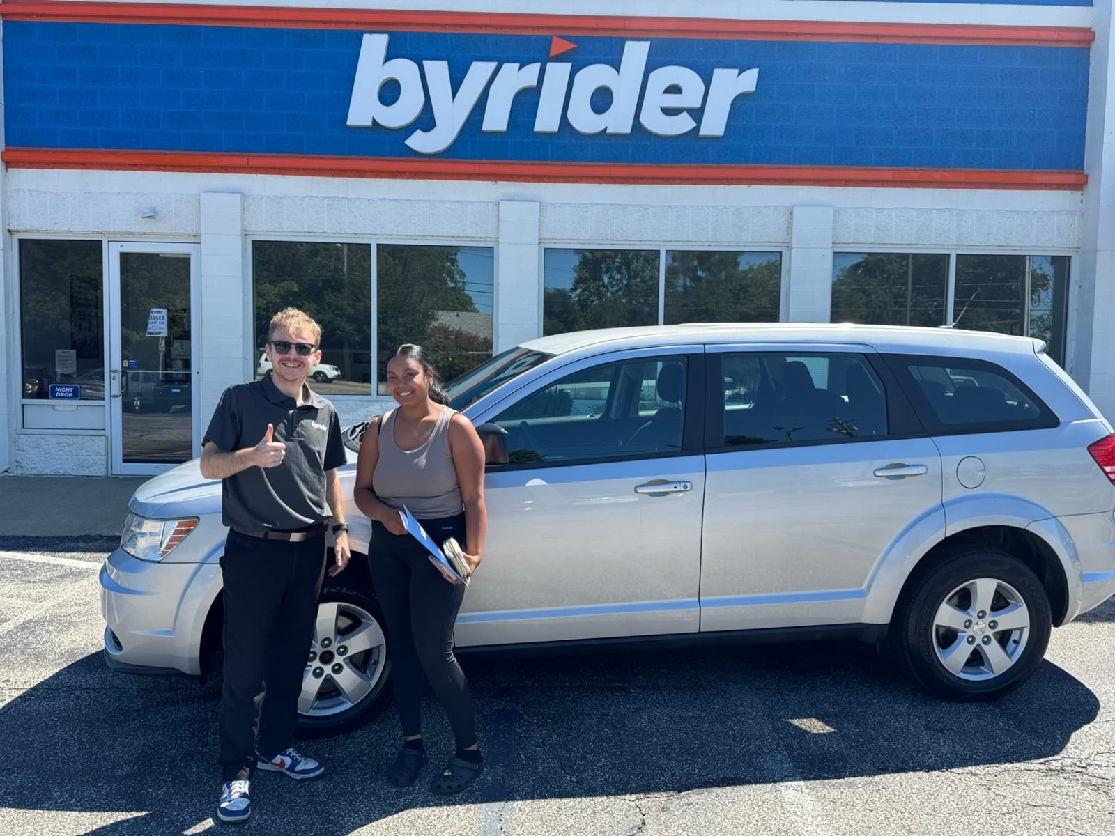 Byrider Ashtabula customer and salesperson beside their used Dodge Journey at the Ashtabula, Ohio dealership