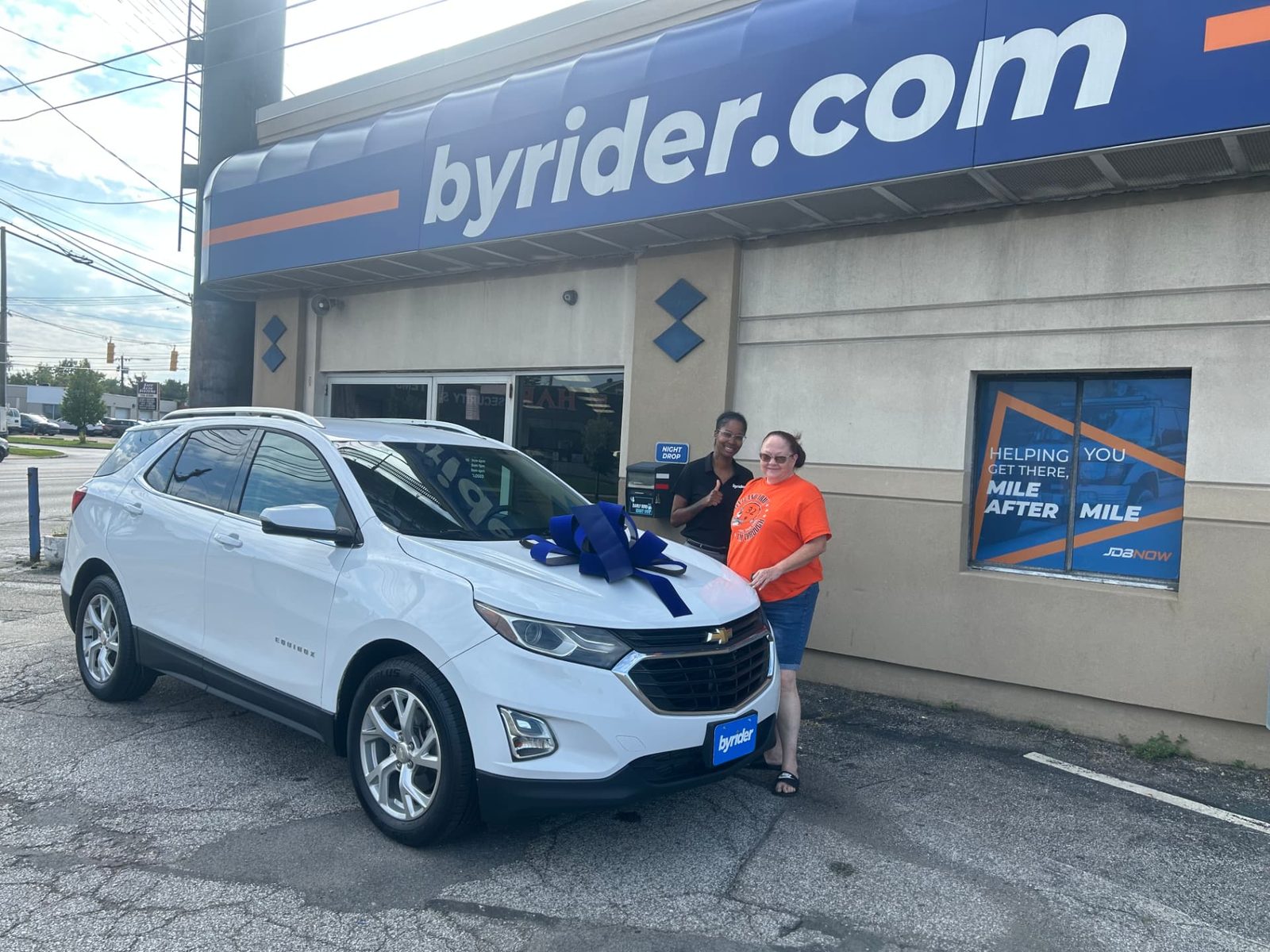 Byrider Cleveland customer and salesperson beside their used Chevrolet Equinox at the Cleveland, Ohio dealership
