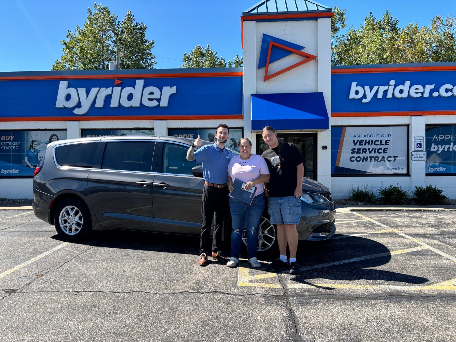 Byrider Amherst customers and salesperson with their used Chrysler Pacifica minivan at the Amherst, Ohio dealership