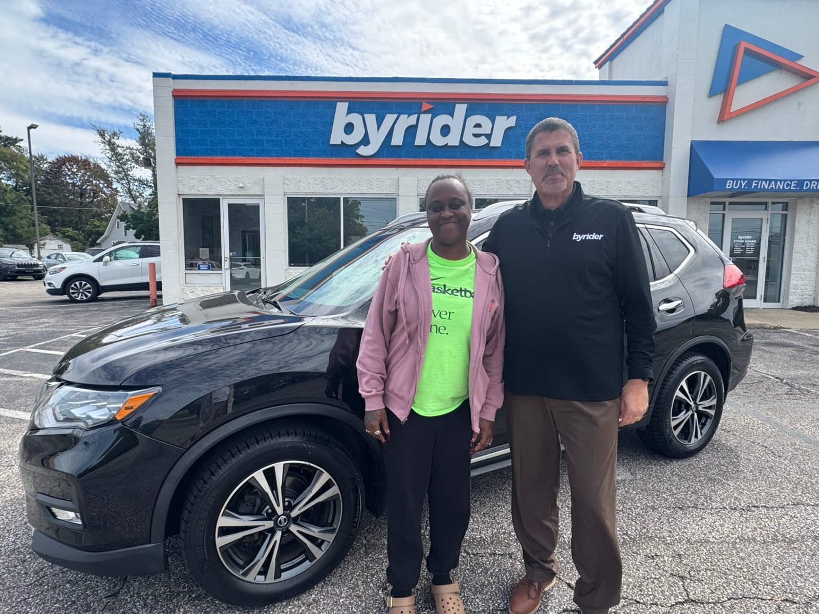 Byrider Ashtabula customer and salesperson beside their used Nissan Rogue at the Ashtabula, Ohio dealership