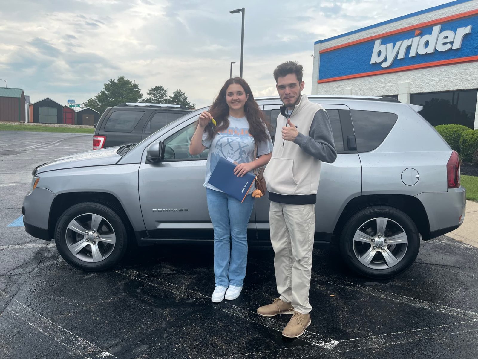 Byrider Ashtabula customers and salesperson beside their used Jeep Compass at the Ashtabula, Ohio dealership