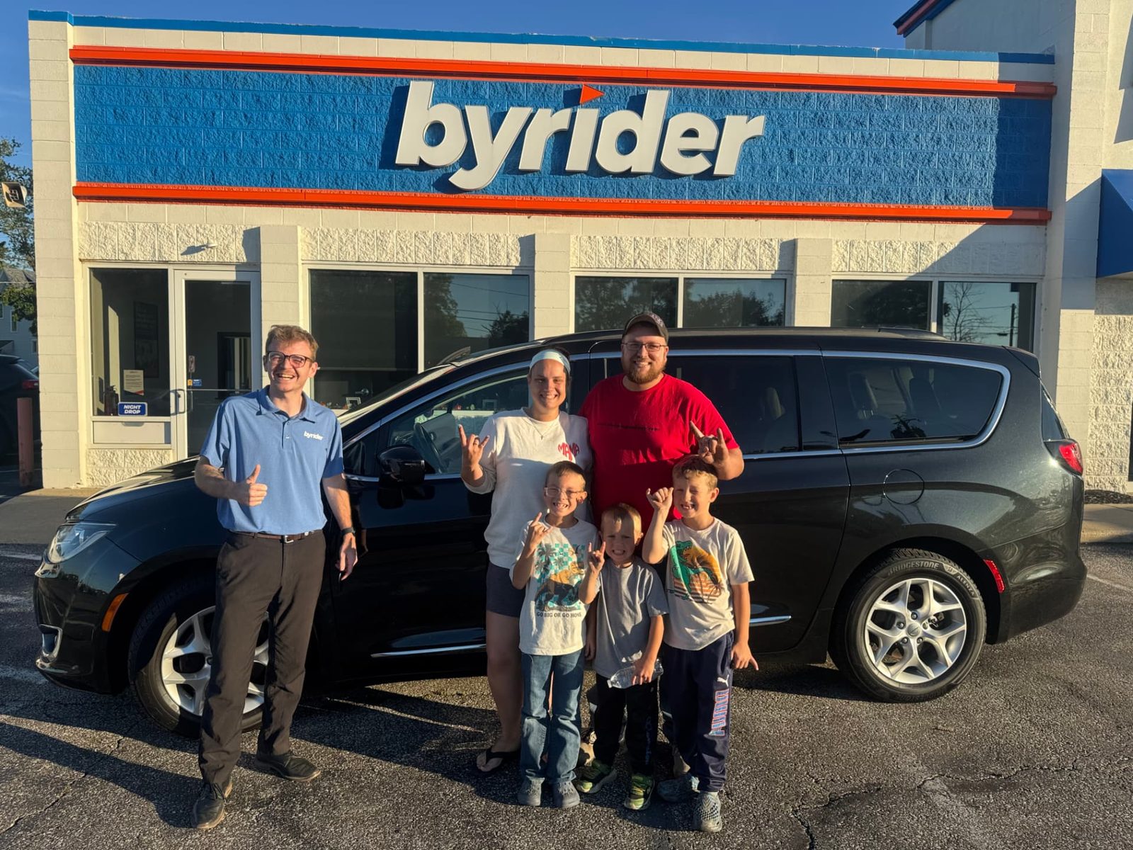 Byrider Ashtabula customers and salesperson beside their used Chrysler Pacifica at the Ashtabula, Ohio dealership