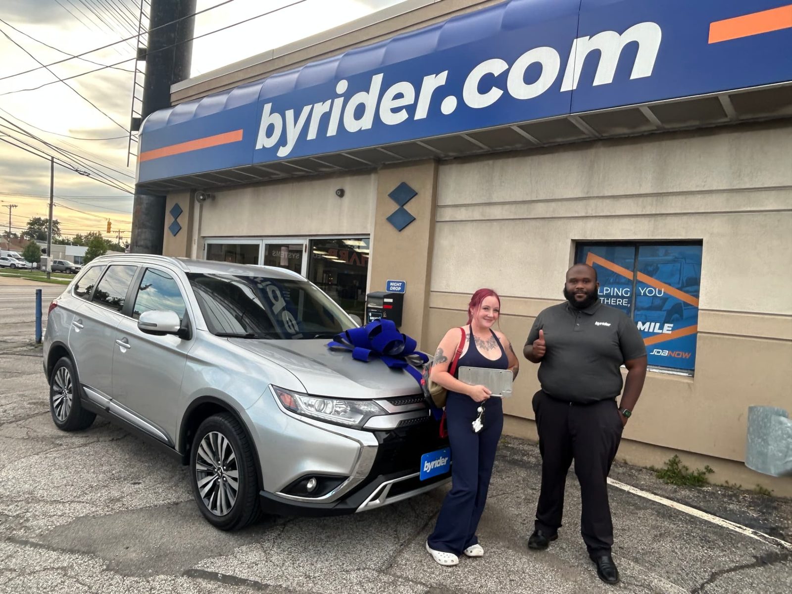 Byrider Cleveland customer and salesperson beside their used Mitsubishi Outlander at the Cleveland, Ohio dealership