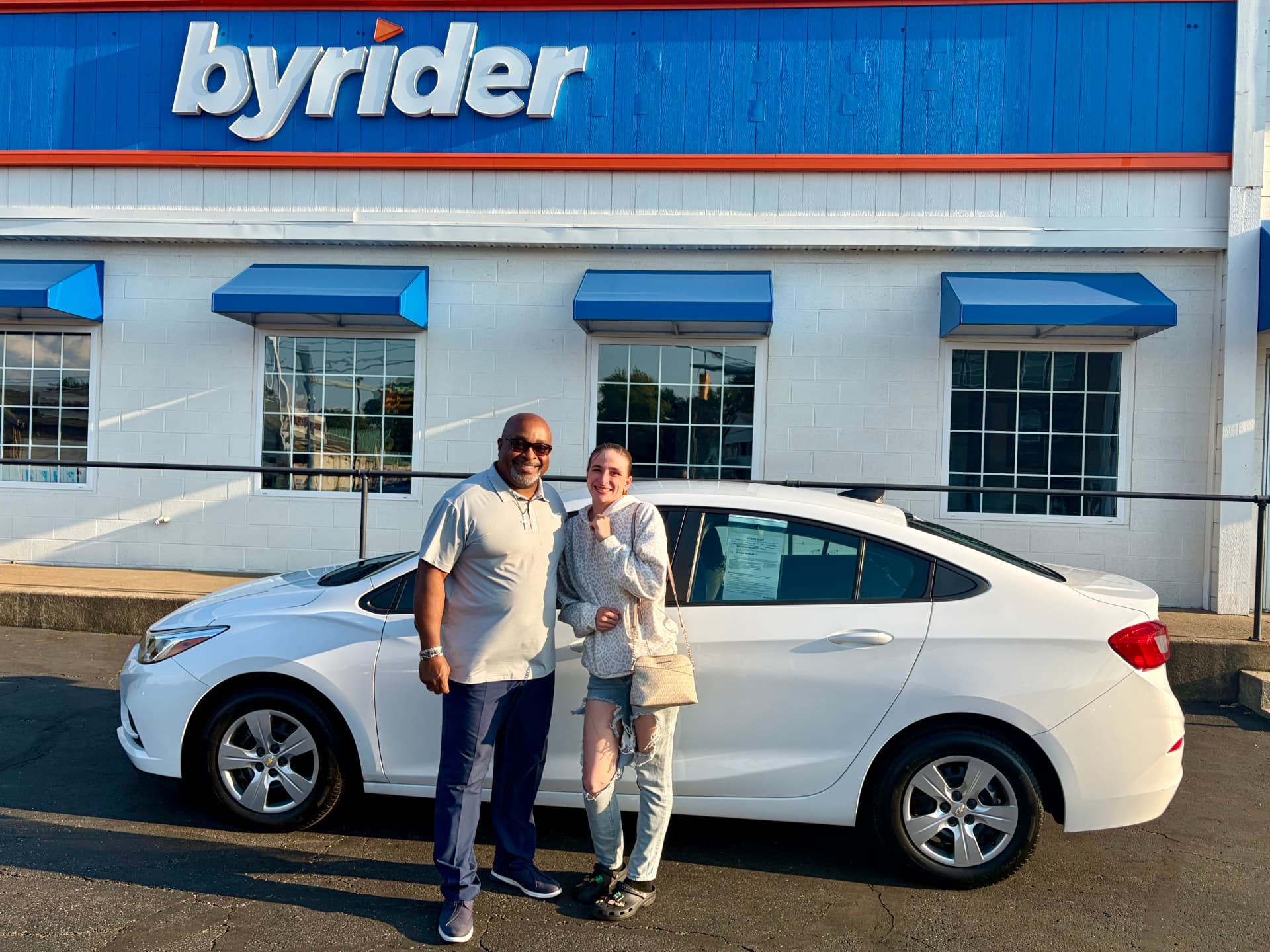 Byrider Canton salesperson and customer beside their used Chevrolet Cruze at the Canton, Ohio dealership