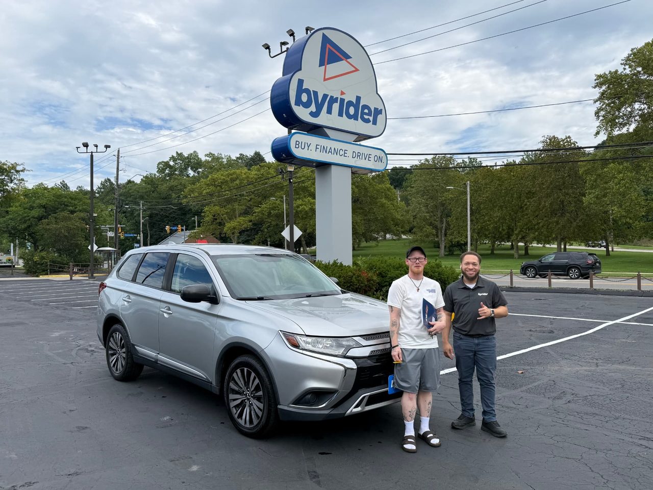 Byrider Euclid customer and salesperson beside their used Mitsubishi Outlander at the Euclid, Ohio dealership