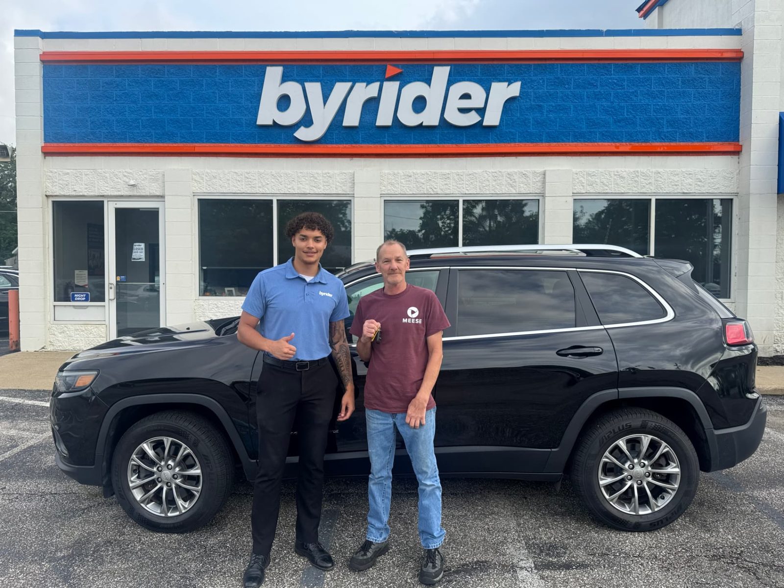 Byrider Ashtabula customer and salesperson beside their used Jeep Cherokee at the Ashtabula, Ohio dealership