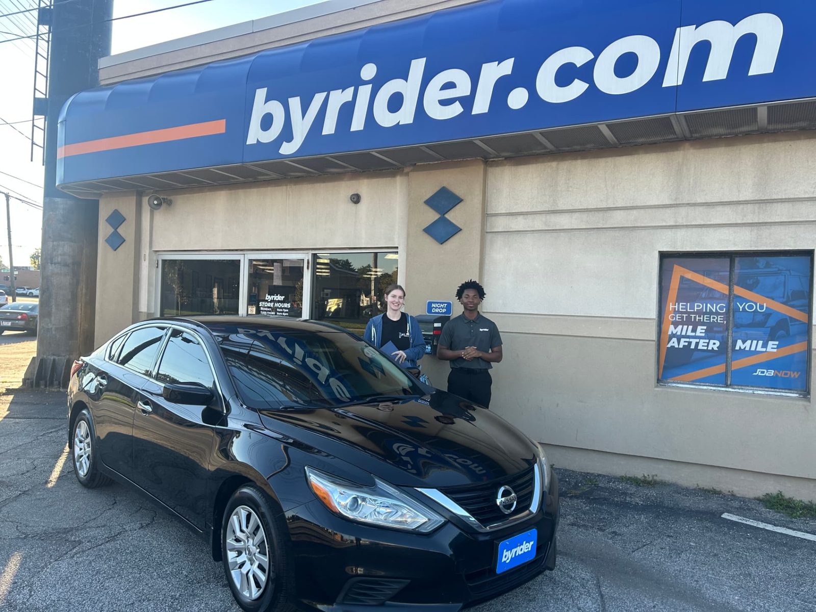 Byrider Cleveland customer and salesperson beside their used Nissan Altima at the Cleveland, Ohio dealership
